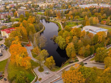 Sonbaharda yukarıdan Valmiera şehri. Cityscape, Bulutlar ve Yapraklarla Panoramik Sonbahar Manzarası. Sonbahar yapraklı şehir manzarası, çiçekler ve yüksek açılı bir ağaç..
