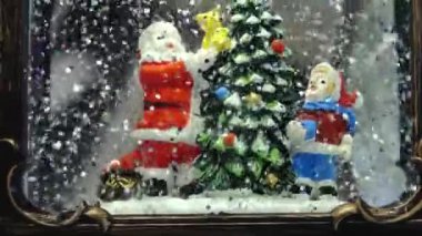 Noel Baba kardan adam kar taneleri ve yüzen simlerle dolu Noel cam kar küresi. Kar yağan Noel kar küresi