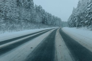 Karla kaplı ağaçlarla dolu soğuk bir ormanın içinden geçen soğuk bir yol. Karlı ormanda kış yolu, ağaçlar ve soğuk hava..