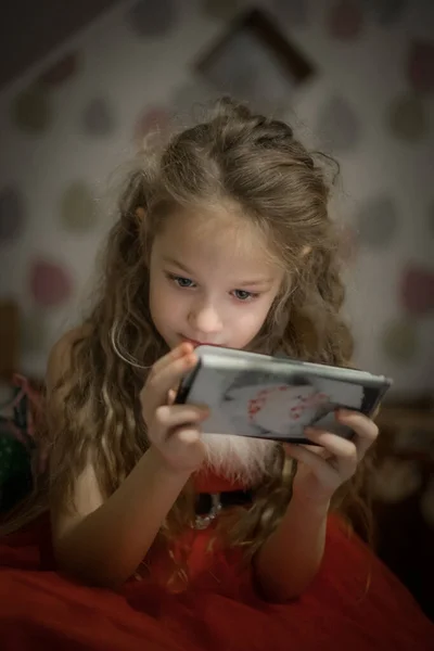 Child Concentration, Female Digital Native Looking Down Holding Technology. A concentrated female digital native looking down while holding technology. Soft selective focus