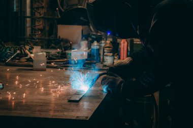 Usta atölyedeki işyerinde kaynak yapıyor. 