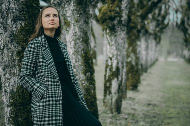 Linden sokağında, koyu renk kareli ceketli, uzun saçlı, bulanık, doğal bir geçmişi olan bir kadın.