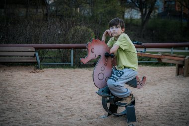 Parktaki çocuk parkındaki bir çocuğun portresi. Üzgün tek başına oturur, arkadaşlarını bekler.