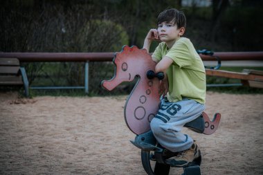 Parktaki çocuk parkındaki bir çocuğun portresi. Üzgün tek başına oturur, arkadaşlarını bekler.