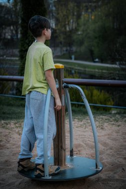 Parktaki çocuk parkındaki bir çocuğun portresi. Üzgün tek başına oturur, arkadaşlarını bekler.