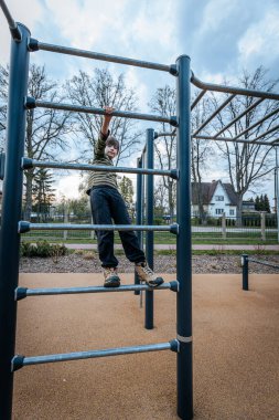 Çocuk, çocuk parkında dinleniyordu. Çocuk parmaklıklarda asılıydı. Gülümseyen mutlu çocuk