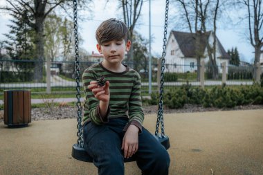 Bir çocuk salıncakta oturuyor. Gülümseyen mutlu çocuk