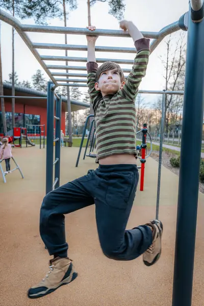 Stock image child rested in the childrens playground. The boy was hanging on the bars. Smiling happy child