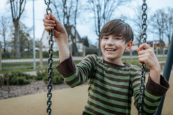 Stock image A boy is sitting on a swing. Smiling happy child