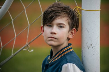 Çocuk kapıda dikiliyor. Genç bir futbolcu topu bekliyor.