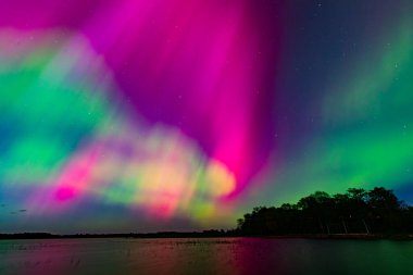 Burtnieks Gölü üzerinde Kuzey Işıkları. Aurora Borealis veya Kuzey Işıkları Letonya. Geceleri suda Aurora yansıması