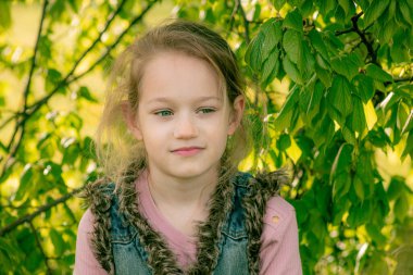 Güzel yeşil gözlü küçük bir kız kameraya poz veriyor.