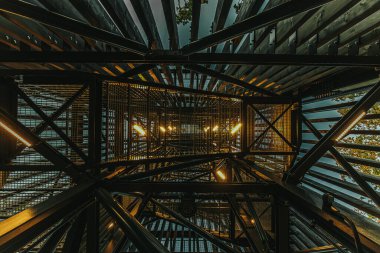 Letonya 'daki Zilakalnas gözetleme kulesinin, açık bir gökyüzünün altında yemyeşil ağaçlarla çevrili çarpıcı manzarası. Kulenin çelik yapısı belirgin bir şekilde...