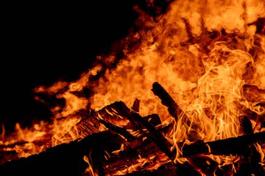Şiddetli bir ateşin dramatik bir görüntüsü karanlık gece gökyüzüne karşı yoğun bir şekilde yanıyor. Parlak turuncu ve sarı alevler alevlerin ham enerjisini ve yıkıcı gücünü vurgular. Boşluğu kopyala.