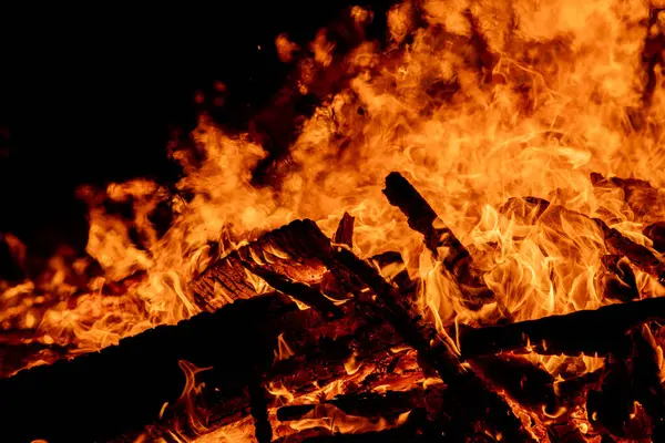 Şiddetli bir ateşin dramatik bir görüntüsü karanlık gece gökyüzüne karşı yoğun bir şekilde yanıyor. Parlak turuncu ve sarı alevler alevlerin ham enerjisini ve yıkıcı gücünü vurgular. Boşluğu kopyala.