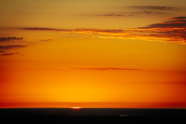 Uçsuz bucaksız orman manzarası üzerinde nefes kesici bir gün doğumu. Canlı turuncu ve sarı renkler karanlık gökyüzüne karışıyor. Dramatik bulutlar manzaraya derinlik katar. Boşluğu kopyala.