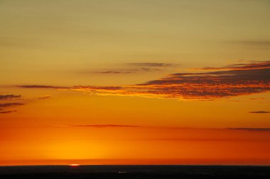 Uçsuz bucaksız orman manzarası üzerinde nefes kesici bir gün doğumu. Canlı turuncu ve sarı renkler karanlık gökyüzüne karışıyor. Dramatik bulutlar manzaraya derinlik katar. Boşluğu kopyala.
