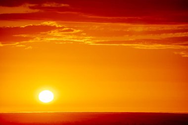 Uçsuz bucaksız orman manzarası üzerinde nefes kesici bir gün doğumu. Canlı turuncu ve sarı renkler karanlık gökyüzüne karışıyor. Dramatik bulutlar manzaraya derinlik katar. Boşluğu kopyala.