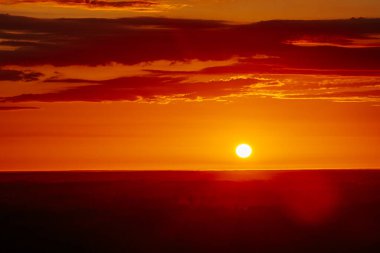 Uçsuz bucaksız orman manzarası üzerinde nefes kesici bir gün doğumu. Canlı turuncu ve sarı renkler karanlık gökyüzüne karışıyor. Dramatik bulutlar manzaraya derinlik katar. Boşluğu kopyala.
