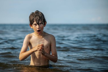 Güneşli bir günde okyanusta oynamanın heyecanını yakalayan, kolları havada suya neşeyle sıçrayan bir çocuk. Sahne, çocukluk ve yaz eğlencesinin tasasız ruhunu simgeliyor.