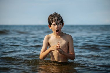 Güneşli bir günde okyanusta oynamanın heyecanını yakalayan, kolları havada suya neşeyle sıçrayan bir çocuk. Sahne, çocukluk ve yaz eğlencesinin tasasız ruhunu simgeliyor.