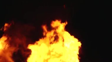 Şiddetli bir ateşin dramatik bir görüntüsü karanlık gece gökyüzüne karşı yoğun bir şekilde yanıyor. Parlak turuncu ve sarı alevler alevlerin ham enerjisini ve yıkıcı gücünü vurgular..