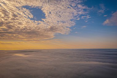 Güneşin ışınlarının bulutları yarıp geçtiği çarpıcı bir hava manzarası sahnenin üzerine huzur verici bir parıltı saçıyor. Işığın ve gölgenin etkileşimi büyüleyici ve sakinleştirici bir etki yaratır.