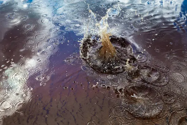 stock image Close-up view of a splash in water, surrounded by concentric ripples and reflections of the sky. The dynamic movement of the splash contrasts with the calm ripples, creating an energetic 