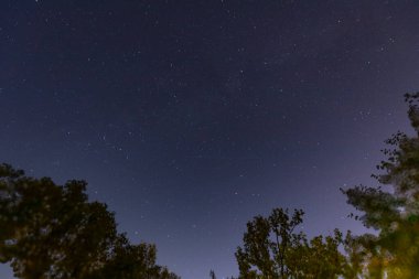 Evren 'in güzelliğini gösteren sayısız yıldızla dolu huzurlu bir gece göğü. Derin mavi arka plan, soluk takımyıldızları ve uzayın enginliğini vurgular.