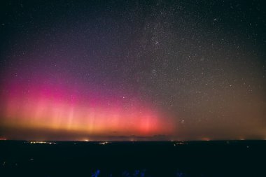 Yıldızlarla dolu nefes kesici bir gece göğü. Pembe ve mor tonlarda soluk bir aurora borealis ile aydınlanıyor. Sessiz bir kasabanın üstündeki ufku aydınlatıyor. Sahne, dingin güzelliği yakalar 