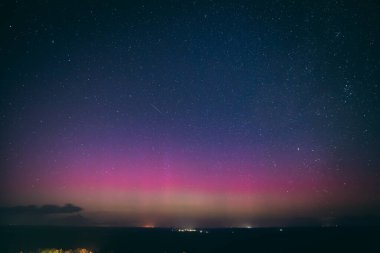 Yıldızlarla dolu nefes kesici bir gece göğü. Pembe ve mor tonlarda soluk bir aurora borealis ile aydınlanıyor. Sessiz bir kasabanın üstündeki ufku aydınlatıyor. Sahne, dingin güzelliği yakalar 