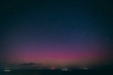Yıldızlarla dolu nefes kesici bir gece göğü. Pembe ve mor tonlarda soluk bir aurora borealis ile aydınlanıyor. Sessiz bir kasabanın üstündeki ufku aydınlatıyor. Sahne, dingin güzelliği yakalar 