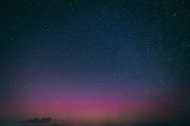 Yıldızlarla dolu nefes kesici bir gece göğü. Pembe ve mor tonlarda soluk bir aurora borealis ile aydınlanıyor. Sessiz bir kasabanın üstündeki ufku aydınlatıyor. Sahne, dingin güzelliği yakalar 