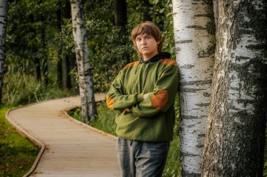 Genç bir adam kollarını kavuşturmuş, bir huş ağacına yaslanmış, düşüncelere dalmış. Sahne, dingin bir ormanda, tahta bir patika boyunca kurulur..