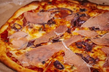 İnce dilimlenmiş jambon, erimiş peynir ve çıtır çıtır soğanlı lezzetli bir pizza. Zengin renkler ve dokular ağız sulandıran maddeleri vurgular.. 