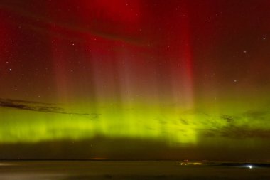 A stunning display of red and green auroras lighting up the night sky, with stars sparkling in the background. The vibrant celestial event creates a mesmerizing, ethereal atmosphere. clipart