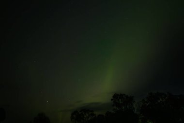  Yumuşak yeşil aurora borealis, yıldızlı bir gece gökyüzünde usulca süzülür ve dingin ve göksel bir manzara yaratır. Uzak yıldızlar, kuzey ışıklarının sönük parıltısında parıldıyor..