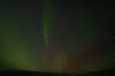  Yumuşak yeşil aurora borealis, yıldızlı bir gece gökyüzünde usulca süzülür ve dingin ve göksel bir manzara yaratır. Uzak yıldızlar, kuzey ışıklarının sönük parıltısında parıldıyor..