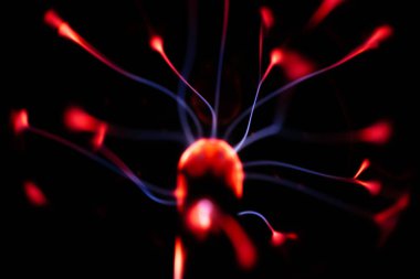 Çekirdeğinden, karanlık bir arkaplana doğru yayılan kırmızı ve mavi elektrik yayı ile parlayan bir plazma topu, canlı ve enerjik bir görüntü oluşturur..