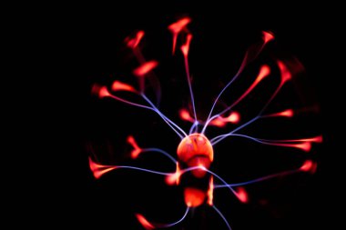 Çekirdeğinden, karanlık bir arkaplana doğru yayılan kırmızı ve mavi elektrik yayı ile parlayan bir plazma topu, canlı ve enerjik bir görüntü oluşturur..