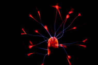 Çekirdeğinden, karanlık bir arkaplana doğru yayılan kırmızı ve mavi elektrik yayı ile parlayan bir plazma topu, canlı ve enerjik bir görüntü oluşturur..