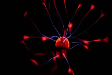 Çekirdeğinden, karanlık bir arkaplana doğru yayılan kırmızı ve mavi elektrik yayı ile parlayan bir plazma topu, canlı ve enerjik bir görüntü oluşturur..