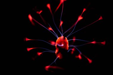 Çekirdeğinden, karanlık bir arkaplana doğru yayılan kırmızı ve mavi elektrik yayı ile parlayan bir plazma topu, canlı ve enerjik bir görüntü oluşturur..