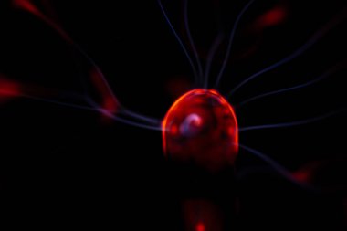 Çekirdeğinden, karanlık bir arkaplana doğru yayılan kırmızı ve mavi elektrik yayı ile parlayan bir plazma topu, canlı ve enerjik bir görüntü oluşturur..