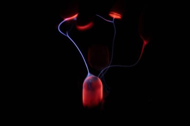 Kırmızı ve mavi enerji yayı ile parlayan bir plazma topu koyu bir arkaplana yayılarak canlı ve heyecan verici bir görsel efekt yaratır.