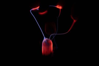 Kırmızı ve mavi enerji yayı ile parlayan bir plazma topu koyu bir arkaplana yayılarak canlı ve heyecan verici bir görsel efekt yaratır.