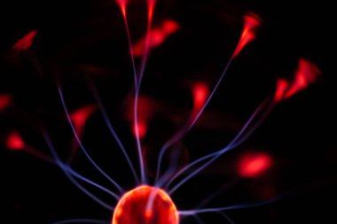 Kırmızı ve mavi enerji yayı ile parlayan bir plazma topu koyu bir arkaplana yayılarak canlı ve heyecan verici bir görsel efekt yaratır.