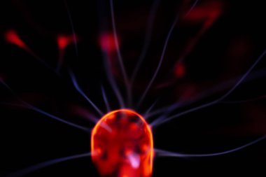 Kırmızı ve mavi enerji yayı ile parlayan bir plazma topu koyu bir arkaplana yayılarak canlı ve heyecan verici bir görsel efekt yaratır.