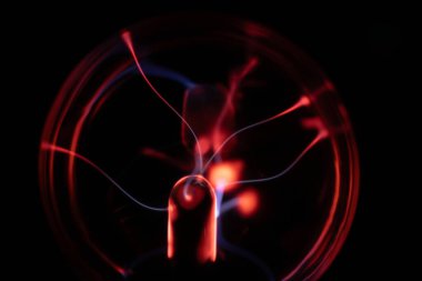 Merkezinden kırmızı ve mavi elektrik yayılan bir plazma topu, karanlık bir arka plana karşı canlı ve büyüleyici bir görsel etki yaratıyor.