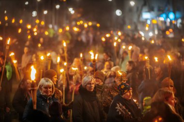 11 Kasım 'da Lpla Günü' nü kutlamak için Valmiera 'da bir meşale geçidi düzenlendi. İnsanlar ellerinde yanan meşaleler ve ulusal bayraklar tutuyor.